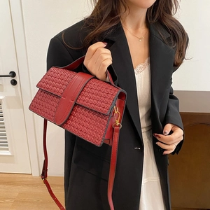 Detail of red woven texture shoulder bag with gold metal hooks and adjustable strap