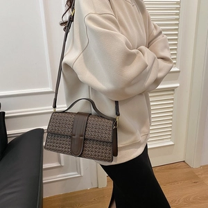 Detail view of deep brown woven texture shoulder bag with premium stitch hardware lock