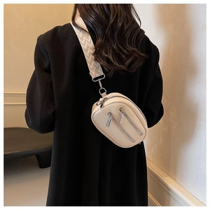 Detail of beige litchi leather round crossbody bag with textured wide shoulder strap