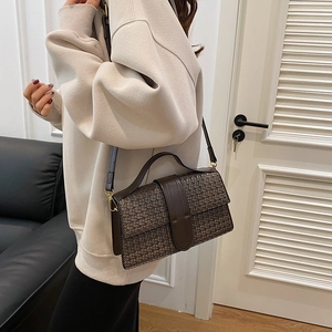 Detailed view of dark brown woven shoulder bag with wide leather strap and buckle