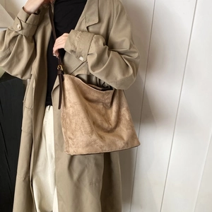 Detail of light brown matte suede tote bag showing texture and adjustable strap on shoulder