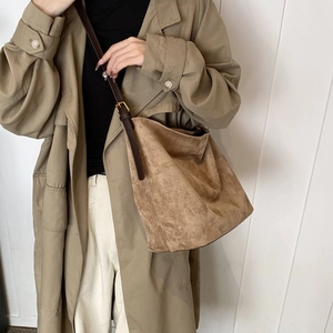 Detailed view of camel suede hobo bag with adjustable brown leather strap worn by a model