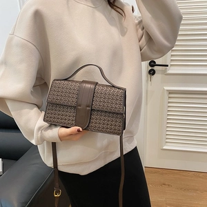 Detail of dark brown woven texture shoulder bag with top handle and magnetic lock flap