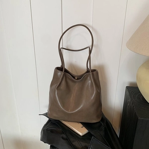 Detail of soft dark brown leather underarm bag with minimalist metallic magnetic closure