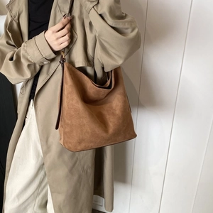 Brown suede tote bag shown on a model with beige coat for a stylish commuter look