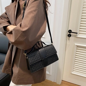 Detail of black woven shoulder bag featuring golden metal hooks and fine stitched textures