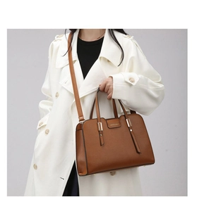 Close-up of brown textured leather handbag featuring gold hardware and a long shoulder strap