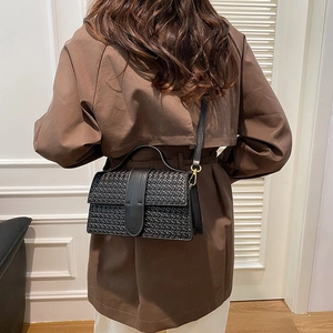 Woven black leather shoulder bag with gold hardware shown on a model's back
