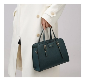 Deep green faux leather handbag detail with gold hardware and embossed fashion logo