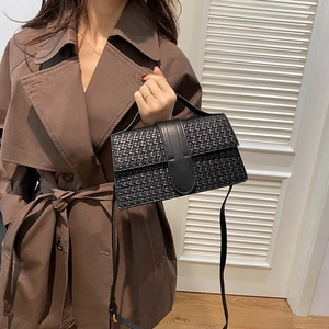 Detail view of black woven texture handbag with lock clasp and shoulder strap