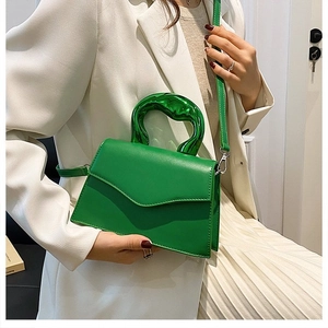 Detail of emerald green crossbody bag with unique translucent green resin handle