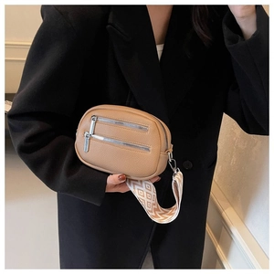 Detail of tan pebble leather crossbody bag with geometric woven wide shoulder strap