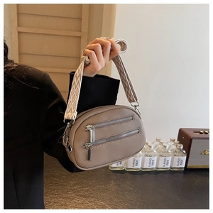 Detail of brown pebbled leather crossbody bag with dual silver zippers and a wide woven strap