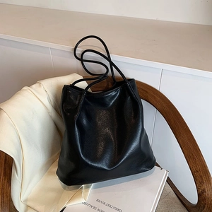 Detailed view of black faux leather tote bag with lychee texture and slim straps