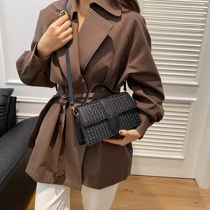 Close-up of black woven leather texture and gold metal hardware on women shoulder bag