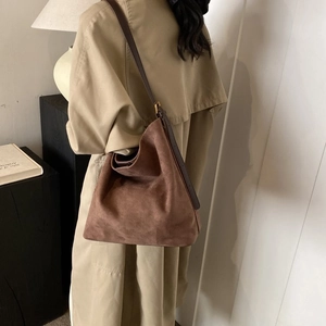 Brown suede tote bag with leather strap shown in a minimalist lifestyle setting