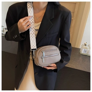 Detail of dual zipper small round crossbody bag with grey litchi texture and wide strap