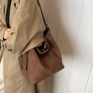 Detail view of brown frosted suede hobo bag styled with a khaki trench coat for daily use