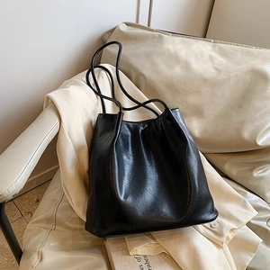 Detail of soft black PU leather tote bag with elegant pleated texture and long handles