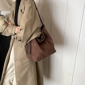 Brown suede hobo bag with large storage space and soft texture shown on model shoulder