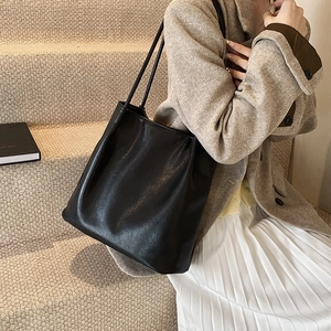 Close-up of minimalist black leather tote bag with slender straps and elegant soft folds