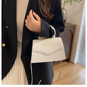 Detailed view of white crossbody bag with silver metal handle and envelope flap closure