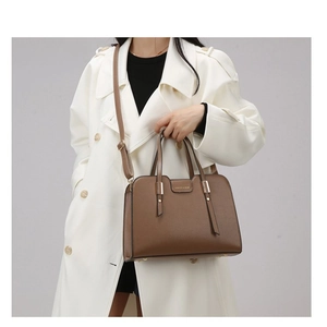 Detail of caramel brown PU leather bag with top handles and adjustable shoulder strap