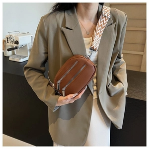 Brown lychee leather crossbody bag featuring dual silver zippers and wide patterned strap