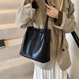 Detailed view of the black leather texture and shoulder strap on the minimalist tote bag