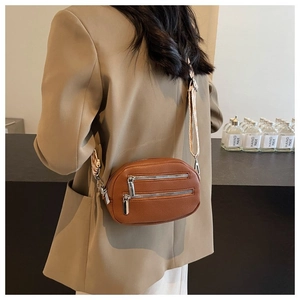Close-up of brown textured leather crossbody bag with adjustable wide woven shoulder strap