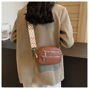 Detail of brown lychee leather crossbody bag with dual silver zippers and chevron strap