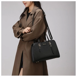 Close-up of black lychee leather crossbody bag with golden hardware on a trench coat