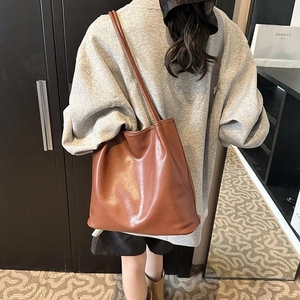 Detail view of a brown faux leather tote bag showing soft texture and long shoulder straps