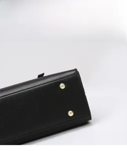 Detail view of the black PU leather handbag bottom with protective gold metal rivets