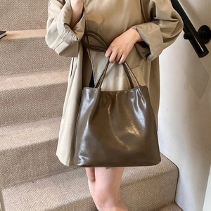 Detail of a dark brown glossy patent leather shoulder bag on a stylish staircase
