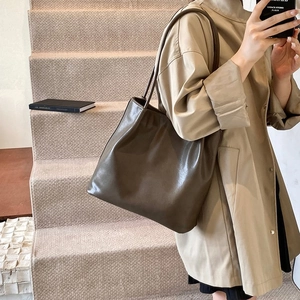 Close-up of minimalist dark chocolate tote bag with smooth leather texture and long straps
