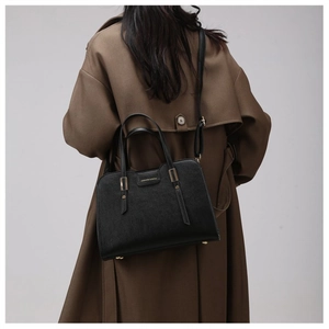Model wearing a black lychee texture tote bag over a brown coat for a size reference