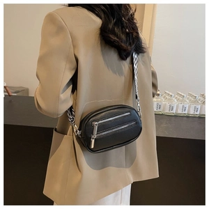 Detail of black crossbody bag with three silver zippers and wide geometric pattern strap
