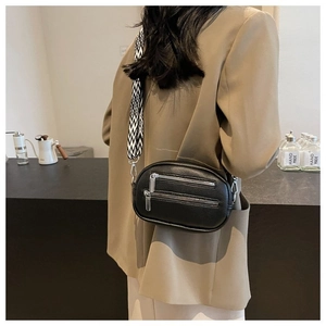 Detail of black pebbled leather crossbody bag with geometric strap and silver zippers