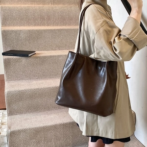 Detail of a dark brown PU leather tote bag worn with a beige trench coat for a commuter style