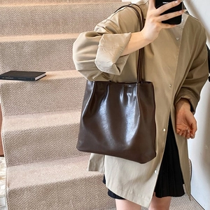 Detail shot of a dark brown glossy PU leather tote bag with slim shoulder straps
