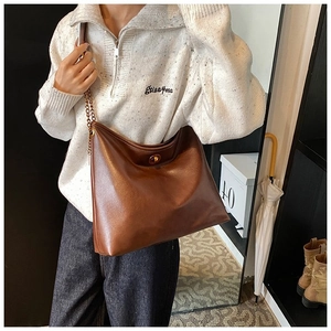 Detail of brown leather hobo bag with gold chain strap and metallic twist lock closure
