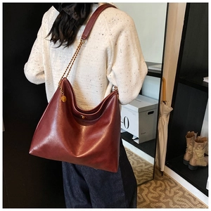 Detail view of large burgundy hobo tote bag with leather strap and gold chain accent