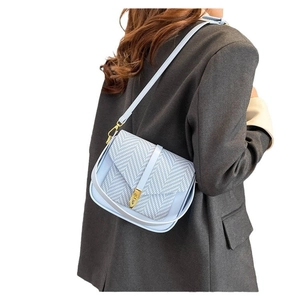 Light blue crossbody bag with woven texture flap and gold lock shown on model