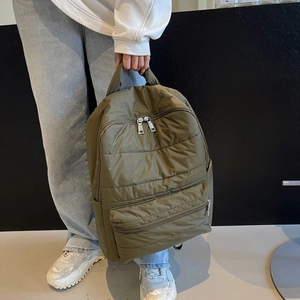 Detail of olive green quilted nylon backpack with metallic zippers and gloss finish