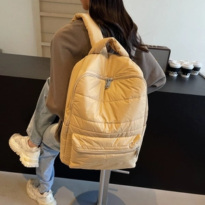 Close-up of ginger yellow quilted nylon backpack with padded straps in a cafe setting