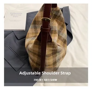 Détail de la bandoulière réglable en cuir rouge avec boucle dorée sur sac à carreaux