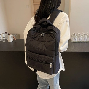 Detailed view of the black quilted nylon backpack with zip closure and stitching