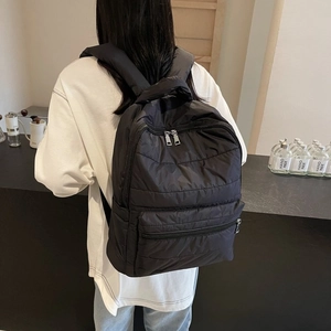 Detailed back view of a black quilted nylon backpack with wide padded shoulder straps