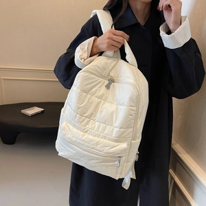 Detail of white quilted nylon backpack with zip front pocket and padded puffer texture